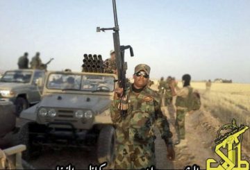 A-man-wearing-Iraqi-army-airborne-jump-wings-with-a-large-calibre-rifle-stands-in-front-of-an-Iranian-Safir-jeep-with-a-107-mm-multiple-rocket-launcher-of-Iraqi-Shia-group-Saraya-Khorasani1