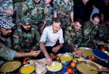 Syria's President Bashar al-Assad (C) joins Syrian army soldiers for Iftar in the farms of Marj al-Sultan village, eastern Ghouta in Damascus, Syria, in this handout picture provided by SANA on June 26, 2016. SANA/Handout via REUTERS/File Photo