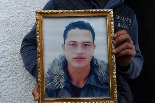 (FILES) This file photo taken on December 23, 2016 shows Walid Amri (back), the brother of 24-year-old Anis Amri, the suspected Berlin truck attacker, posing with a portrait of his brother Anis in front of the family house in the town of Oueslatia, in Tunisia's region of Kairouan.
German police on December 28, 2016 detained a Tunisian national on suspicion of having ties to Anis Amri, the suspected Berlin truck attacker gunned down by Italian police, prosecutors said. Twelve people were killed and dozens injured on December 19, when Amri is believed to have hijacked a truck and used it to mow down people at a Berlin Christmas market.
 / AFP PHOTO / FETHI BELAID