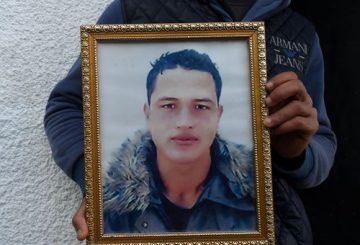 (FILES) This file photo taken on December 23, 2016 shows Walid Amri (back), the brother of 24-year-old Anis Amri, the suspected Berlin truck attacker, posing with a portrait of his brother Anis in front of the family house in the town of Oueslatia, in Tunisia's region of Kairouan. German police on December 28, 2016 detained a Tunisian national on suspicion of having ties to Anis Amri, the suspected Berlin truck attacker gunned down by Italian police, prosecutors said. Twelve people were killed and dozens injured on December 19, when Amri is believed to have hijacked a truck and used it to mow down people at a Berlin Christmas market. / AFP PHOTO / FETHI BELAID