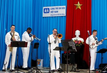 Members of U.S. Seventh Fleet Band perform as a statue of late Vietnamese revolutionary leader Ho Chi Minh is seen in the background, as part of the U.S aircraft carrier USS Carl Vinson to Vietnam, at the Da Nang SOS Children's Village in Danang, Vietnam March 6, 2018. REUTERS/Kham