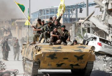 Syrian Democratic Forces (SDF) fighters ride atop of military vehicle as they celebrate victory in Raqqa, Syria, October 17, 2017. REUTERS/Erik De Castro