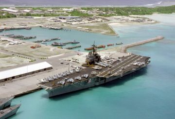 An aerial port bow view of the aircraft carrier USS SARATOGA (CV-60) tied up at pier. This is the first time an aircraft carrier has visited the island.