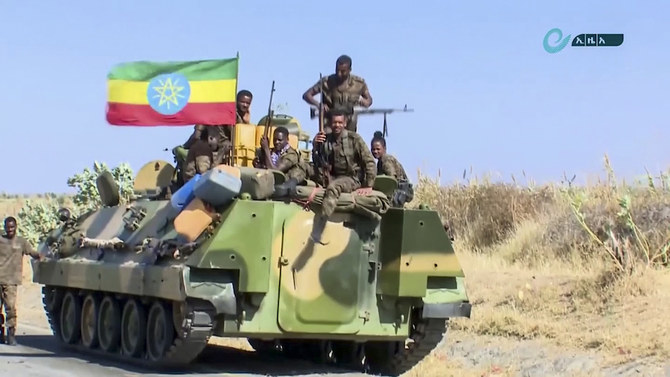 This image made from undated video released by the state-owned Ethiopian News Agency on Monday, Nov. 16, 2020 shows Ethiopian military sitting on an armored personnel carrier next to a national flag, on a road in an area near the border of the Tigray and Amhara regions of Ethiopia. Ethiopia's prime minister Abiy Ahmed said in a social media post on Tuesday, Nov. 17, 2020 that "the final and crucial" military operation will launch in the coming days against the government of the country's rebellious northern Tigray region. (Ethiopian News Agency via AP)